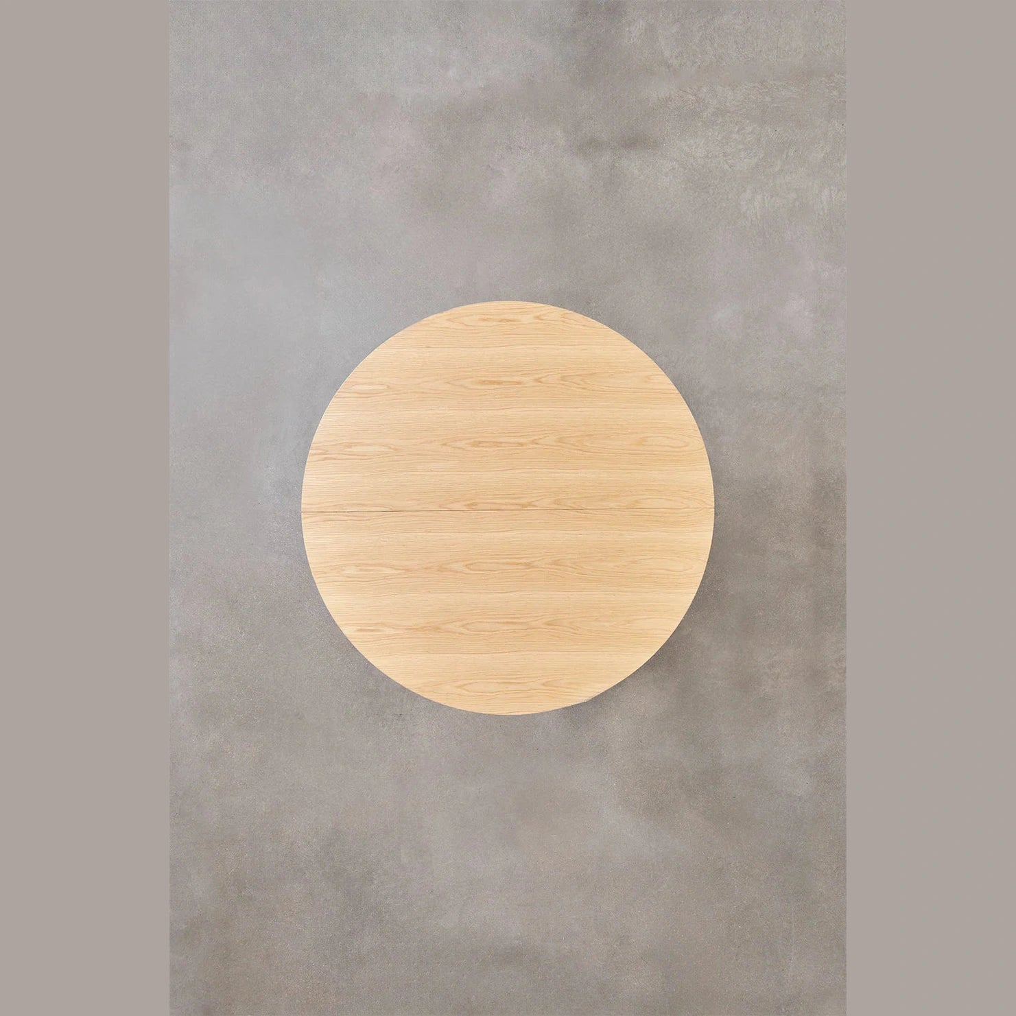 Salle à manger moderne avec table ronde en bois clair et chaises design.